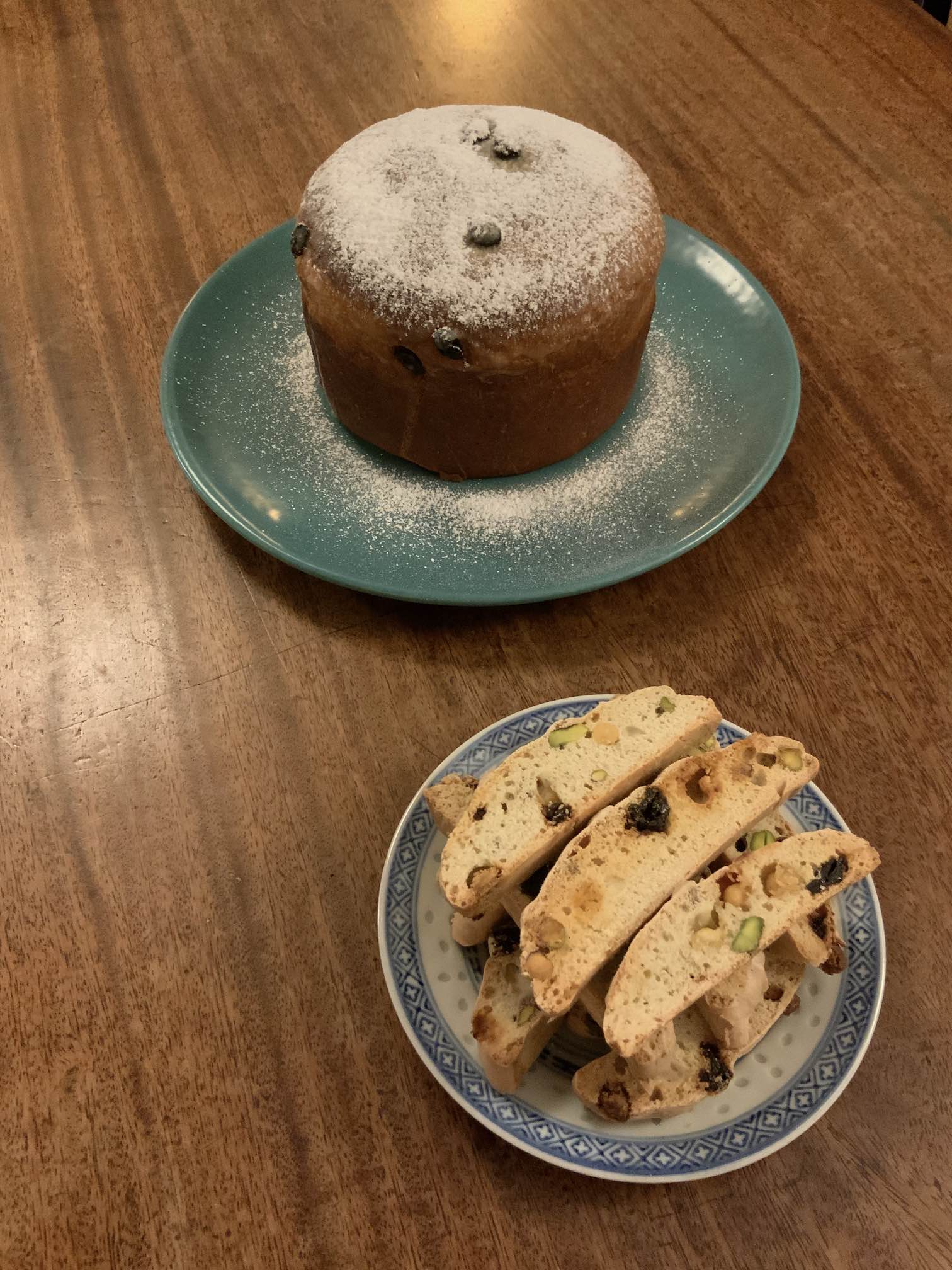 Photo of crunchy little fruit and nut filled bread slices, and a tall round bread/cake dusted with icing sugar.