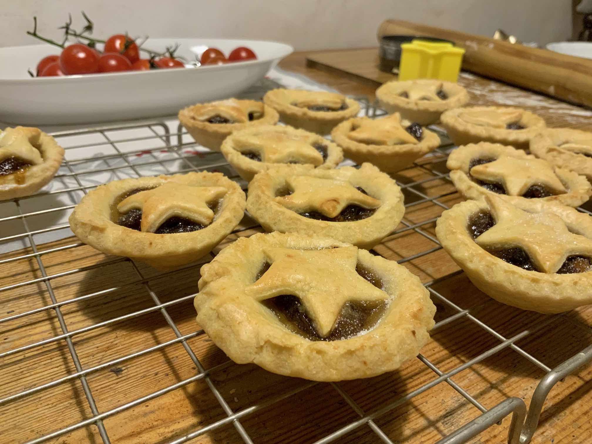 Close-up photo of mince pies with star shaped pastry top on a cooling rack.