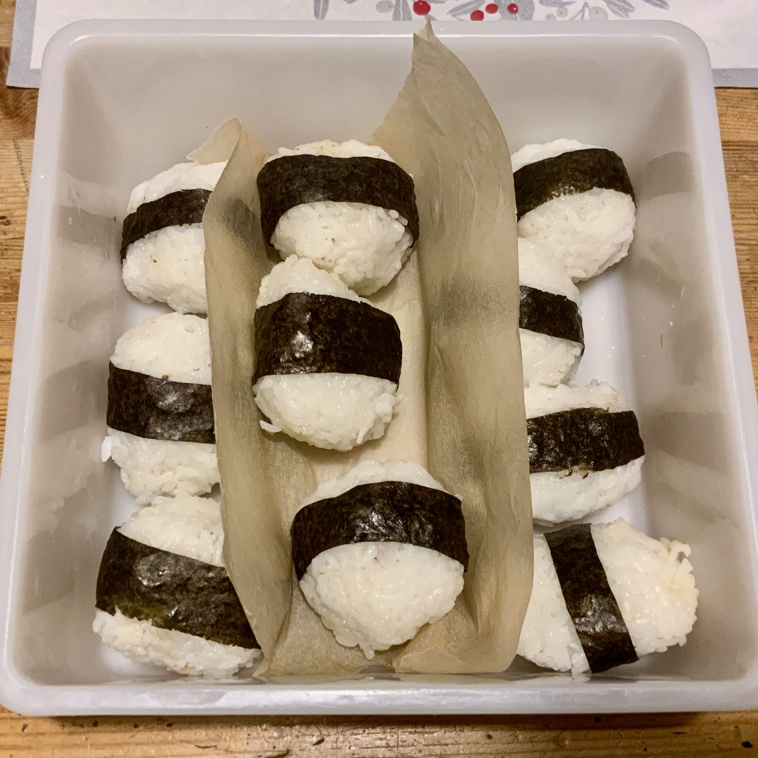 Photo of ten rice balls, each wrapped in a band of nori seaweed.