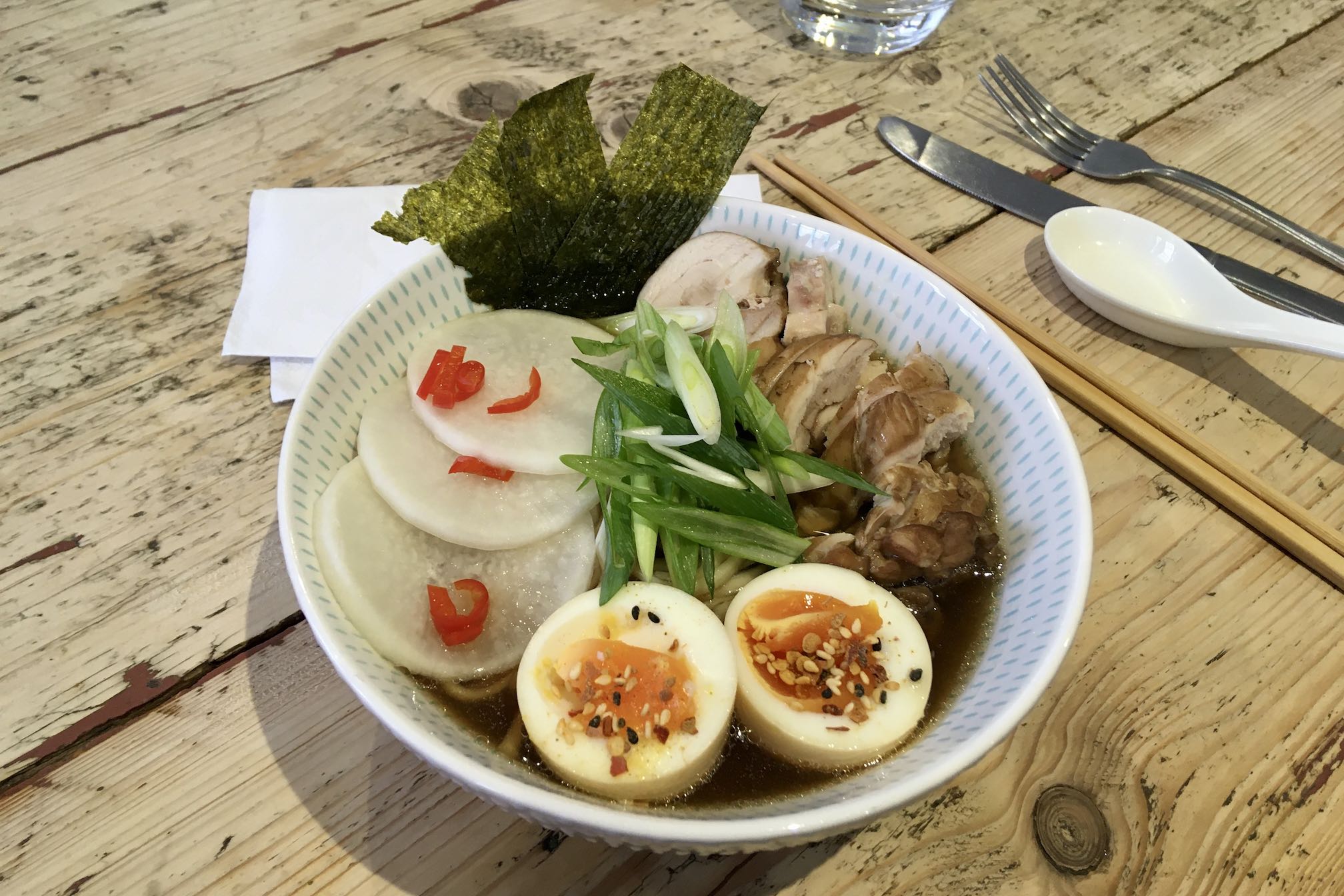Photo of ramen bowl with chicken, eggs, spring onions, daikon and nori