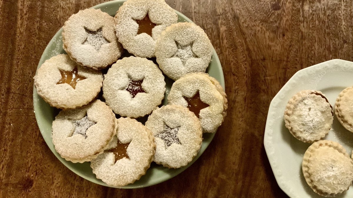Photo of Linzer Augen cookies with stars cut out the middle, and some mince pices on the right