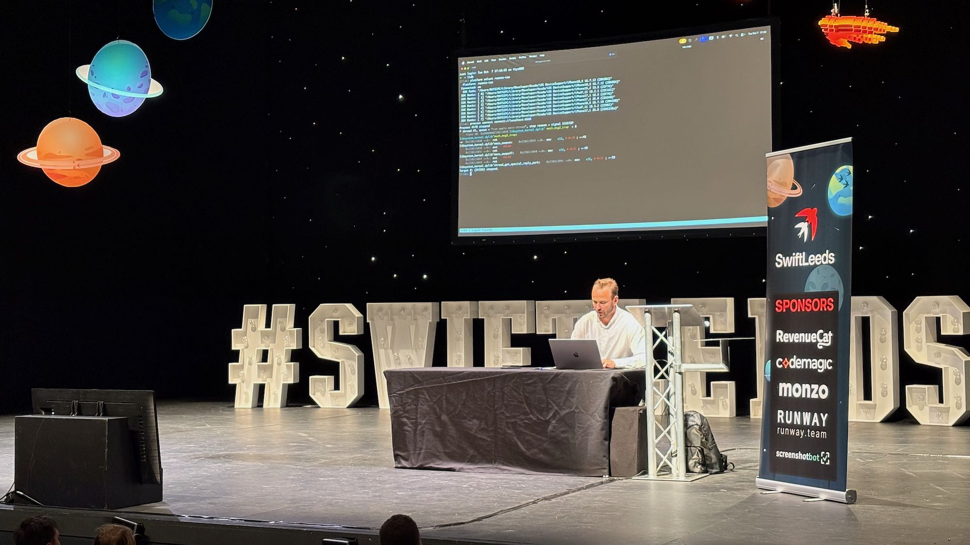 Photo of Cyril on stage at the conference sitting using lldb in a demo.
