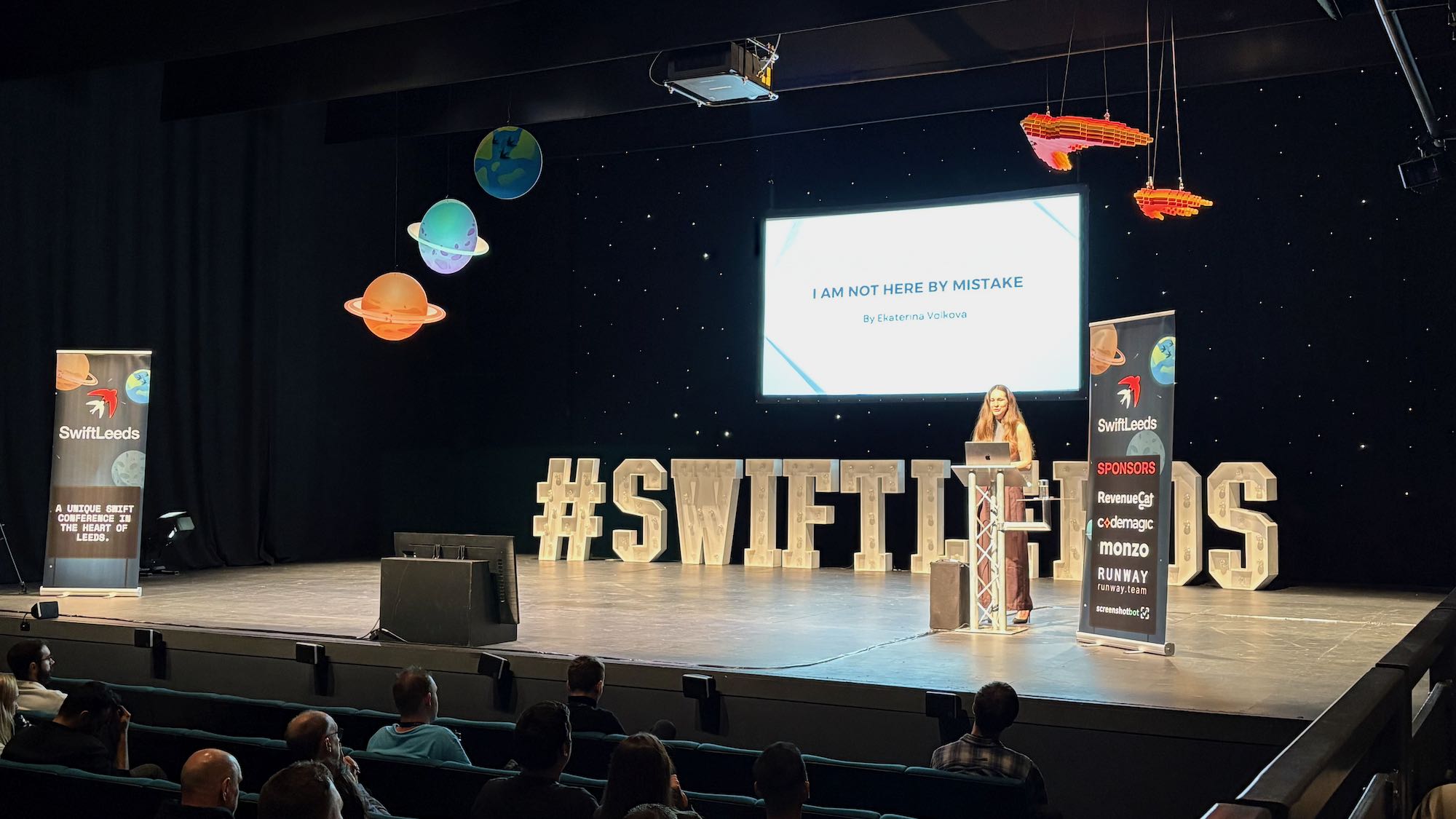 Photo of Ekaterina on stage at the conference. Title is “I am not here by mistake”.