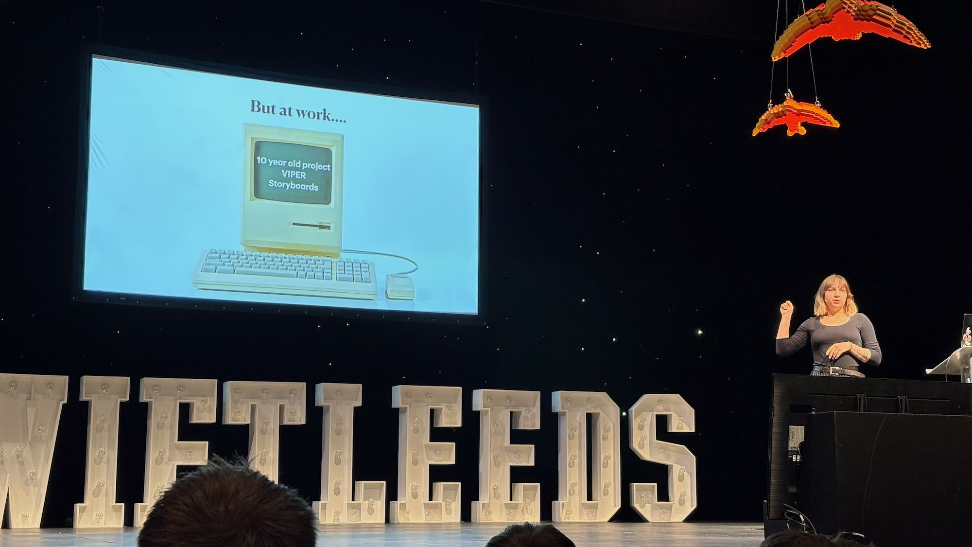 Photo of Oksana on stage at the conference. Slide says “But at workæ 10 year old project, VIPER, Storyboards”.